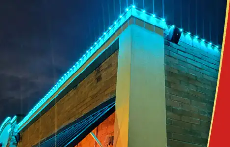 Close up view of a commercial building roofline with bright blue permanent lighting installed along the edge.