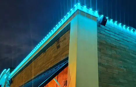 Detail view of a commercial retail building roofline with bright blue permanent lighting installed along the edge.