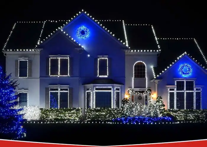 A modern stucco home with professionally installed white LED Christmas lights and blue wreaths.